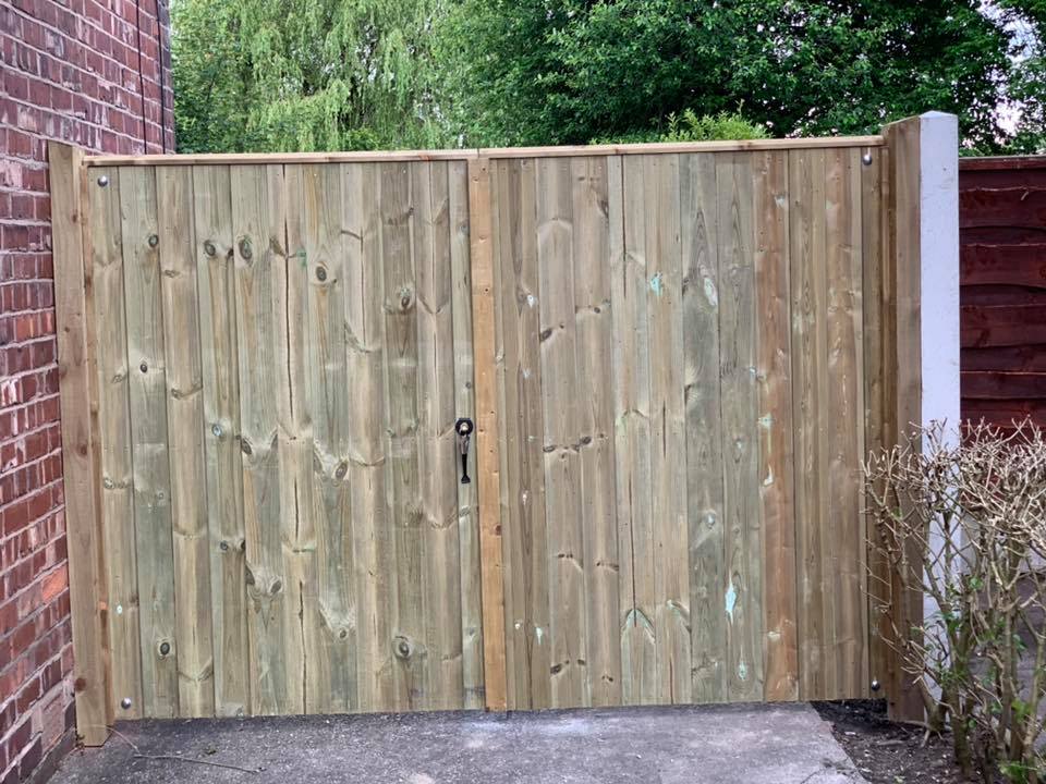 Double wooden tongue and groove garden gates installed between brick and fence, providing privacy and durability.